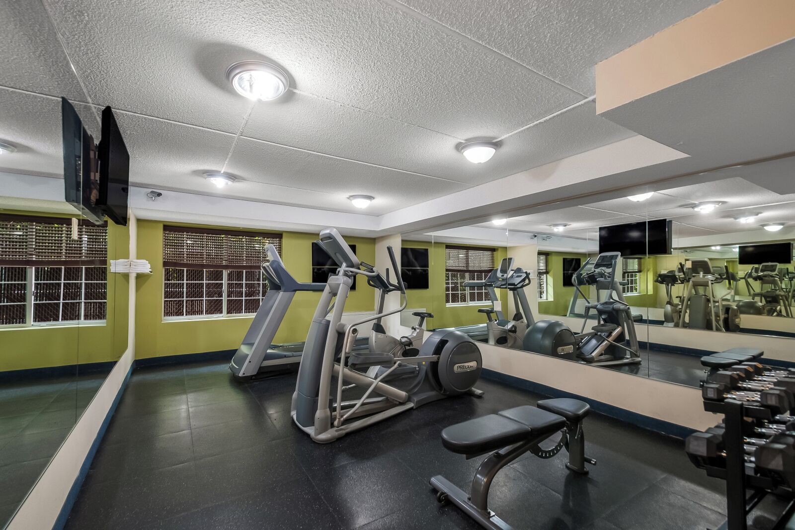 Et fitnesscenter med løbebånd, crosstrainere og vægtbænke.