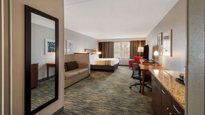 A hotel room with a bed, a desk, a chair, a sofa, and a large mirror. - Country Inn & Suites by Radisson, Fredericksburg South (I-95), VA (Fredericksburg)