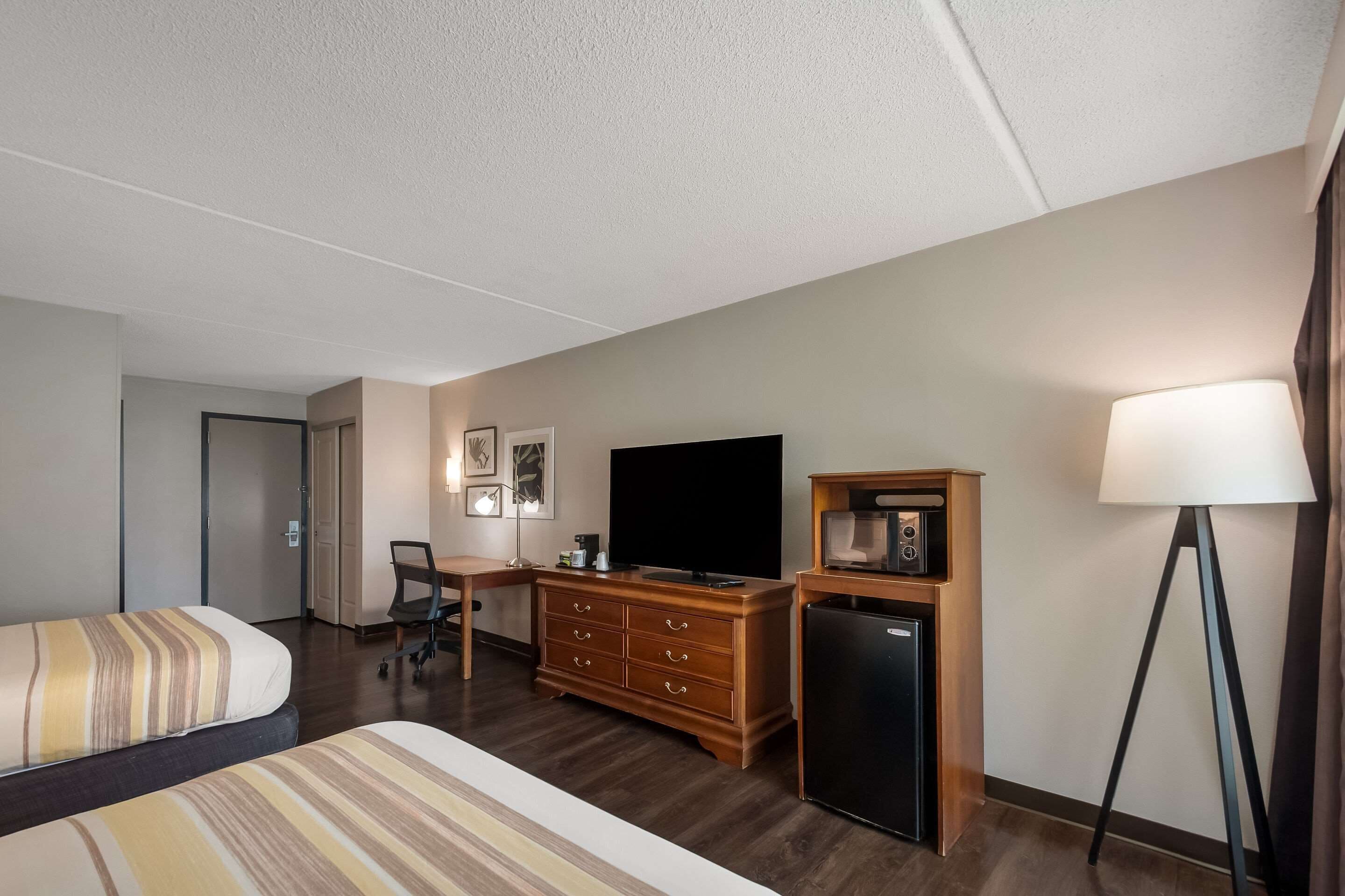 Hotelkamer met een bed, bureau, televisie, kledingkast, koelkast en lamp.