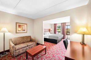 A hotel room with a sofa, a bed, a table, and a lamp. - Quality Inn Selma - Smithfield (Selma)
