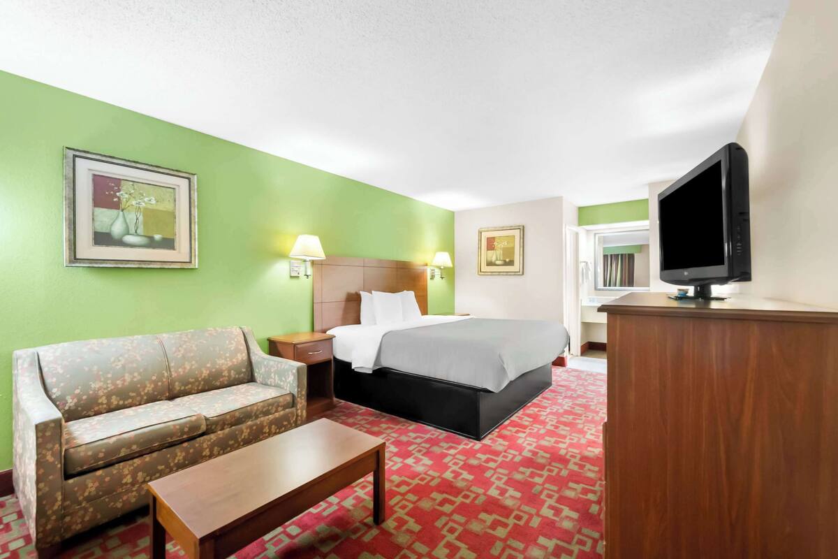 Een hotelkamer met een bank, een bed, een bureau, een televisie en twee wandlampen.
