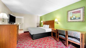Ein Hotelzimmer mit einem Bett, einem Schreibtisch mit Stuhl, einem Fernseher und einem Bild an der Wand.