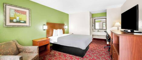A hotel room with a bed, a desk, a television, a chair, and a painting on the wall.