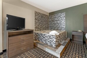Une salle de bain moderne dotée d’une grande baignoire, d’un téléviseur à écran plat et d’un meuble-lavabo en bois.