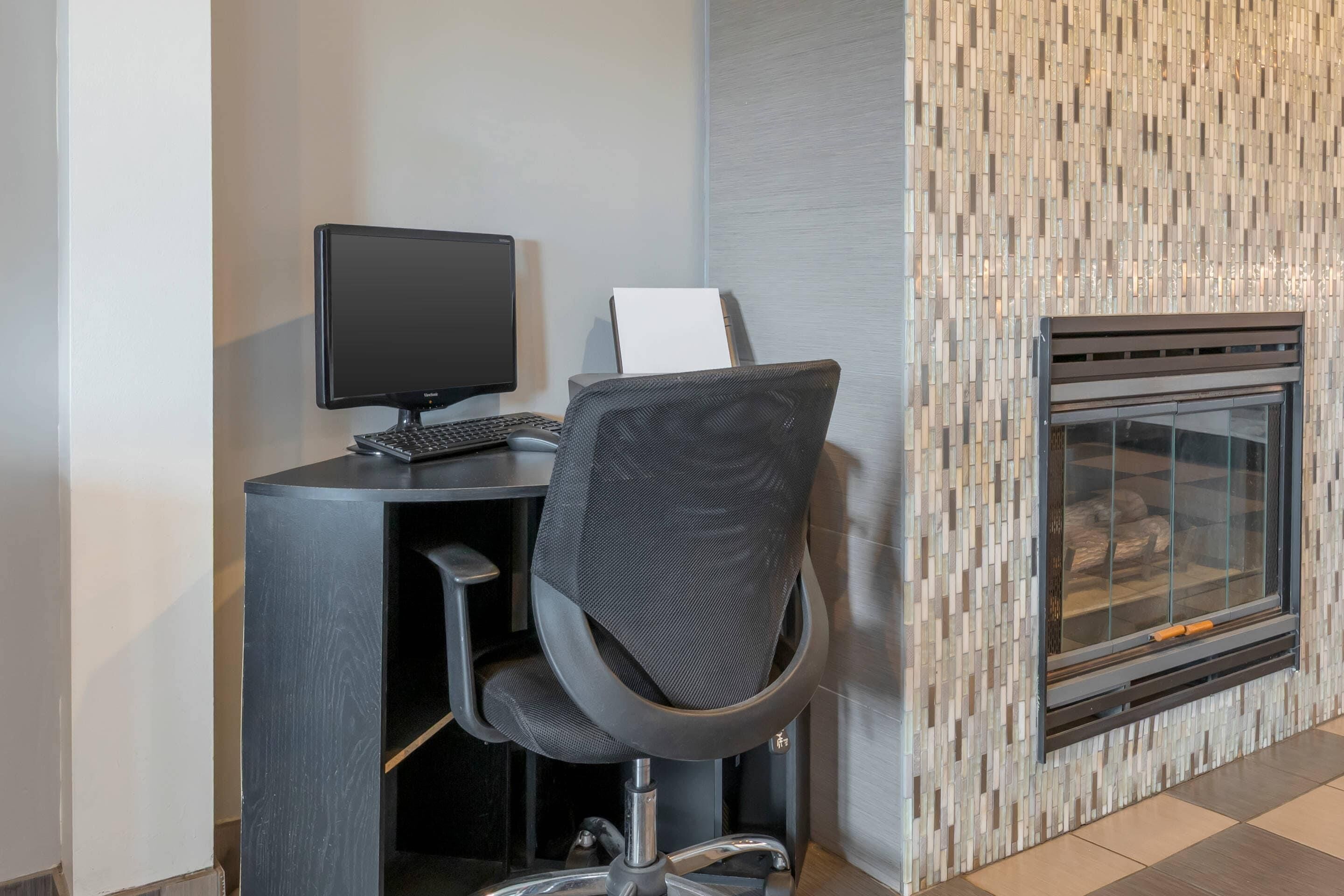 Una silla de oficina moderna con un teclado y un monitor, una chimenea y una pared de azulejos.