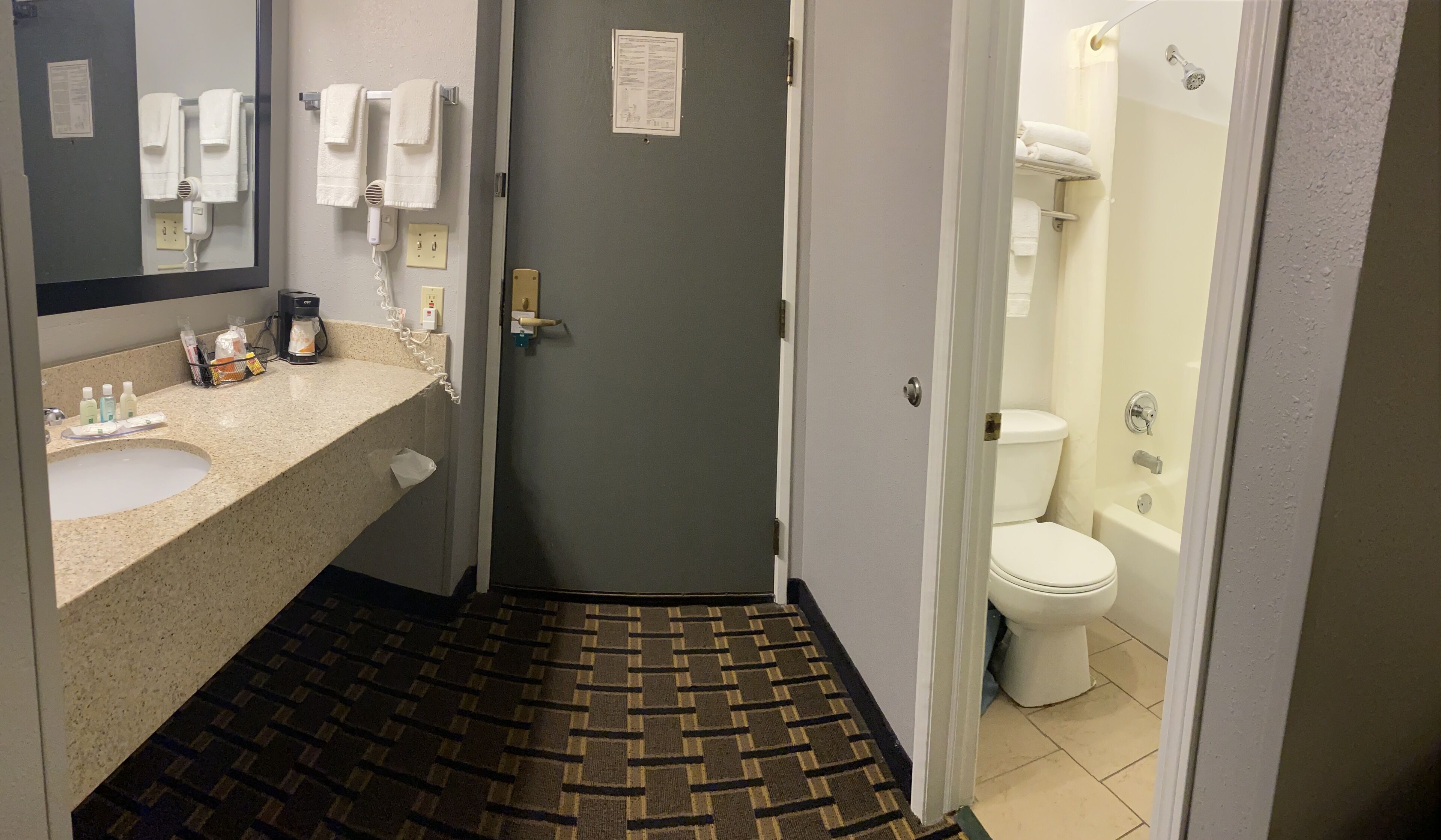 A hotel bathroom with a sink, towel rack, and a shower area.