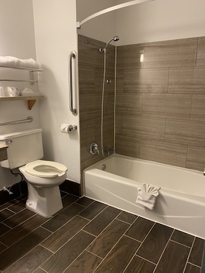 Un baño con inodoro, ducha con puerta de vidrio y bañera.
