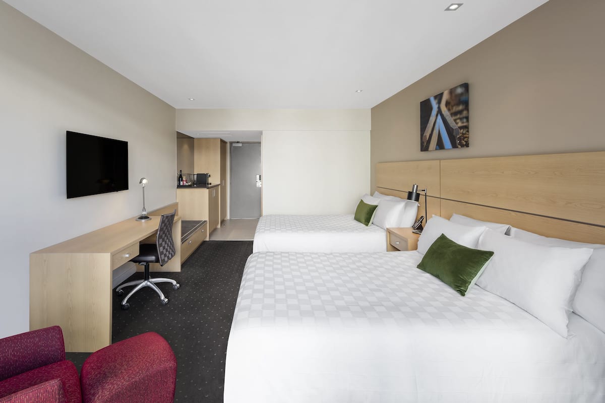 Een hotelkamer met twee bedden, een bureau, een stoel en een televisie.