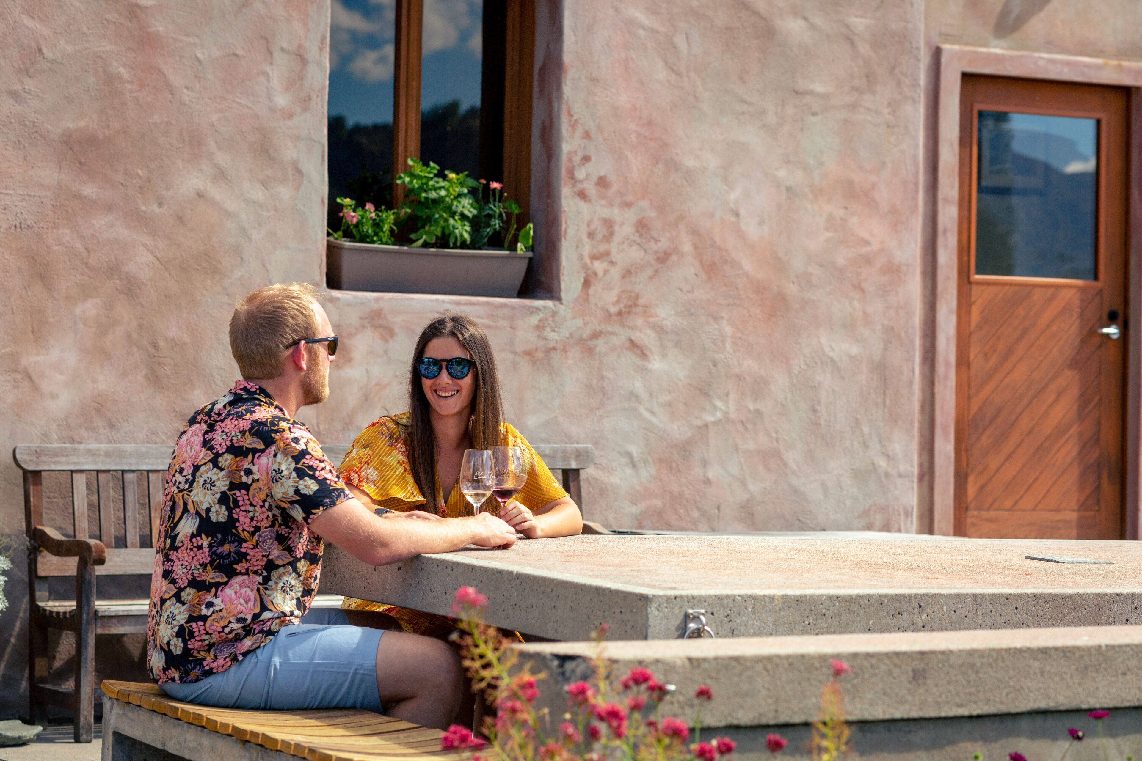 Una pareja sentada en una mesa al aire libre con vista a un edificio y una puerta.