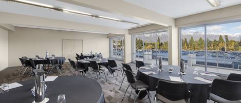 A conference room with round tables, chairs, and a view of mountains through large windows.
