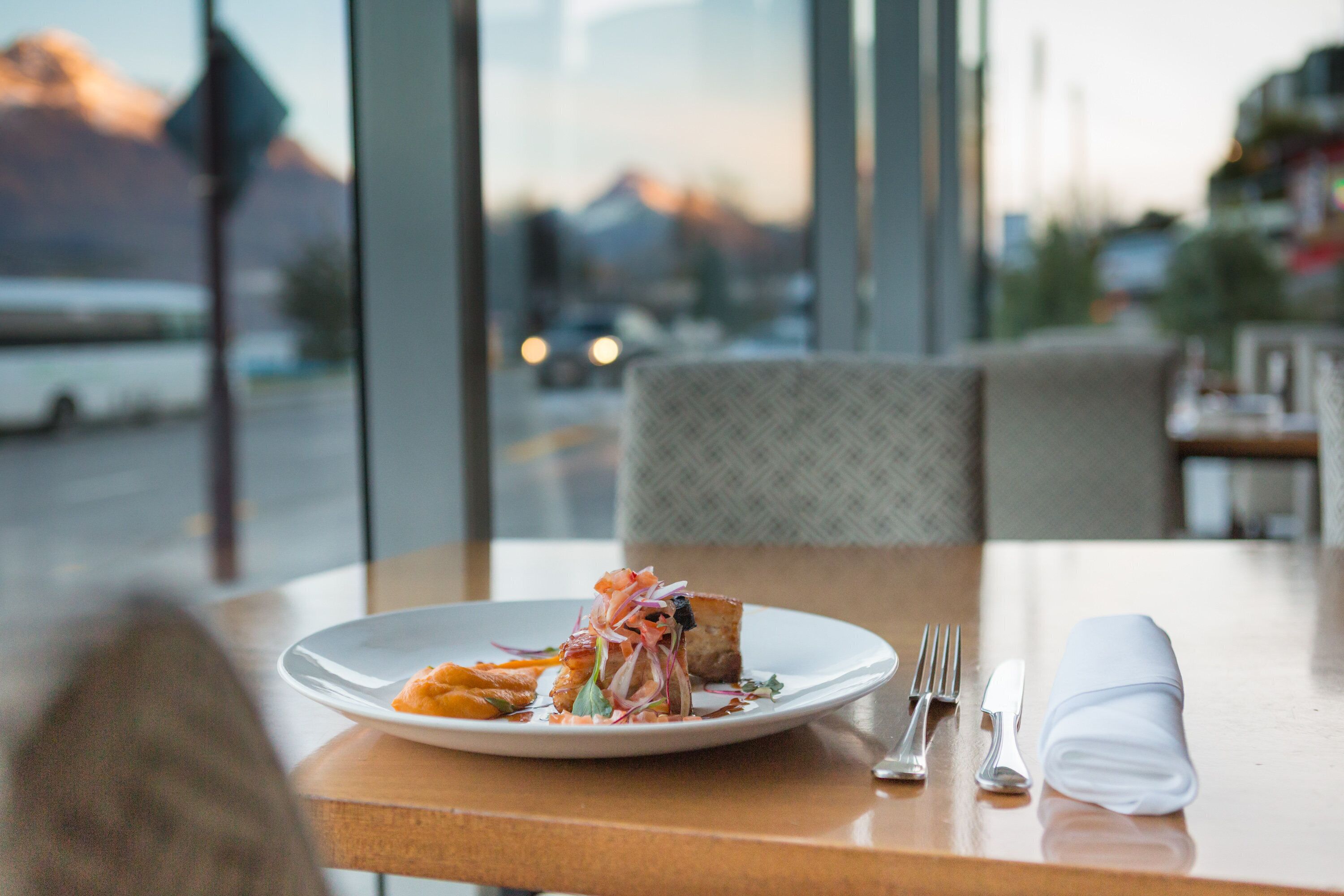 A dining table with a plate of food, cutlery, and a napkin.