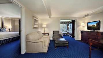 A hotel room with a bed, a sofa, a chair, a TV, and a dresser.