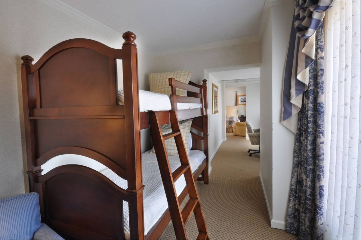 A hotel room with a bunk bed, a desk, and a chair.