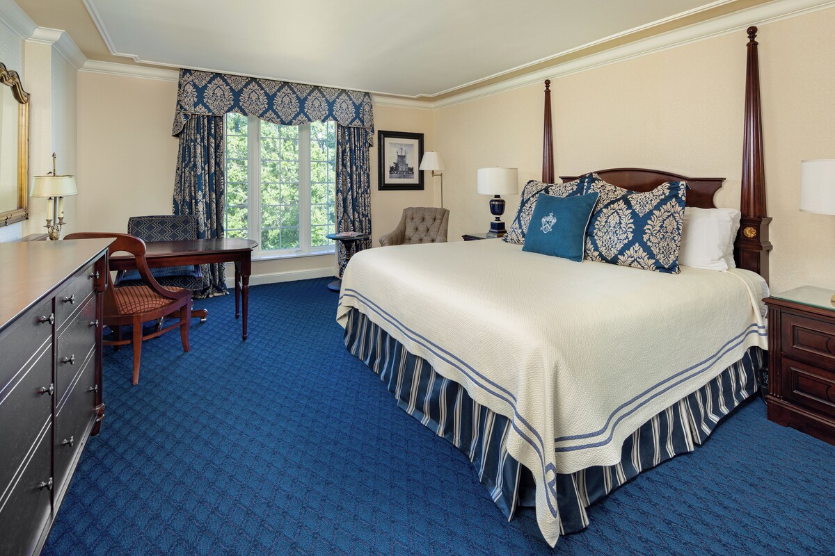 A bedroom with a large bed, a desk, and a chair.