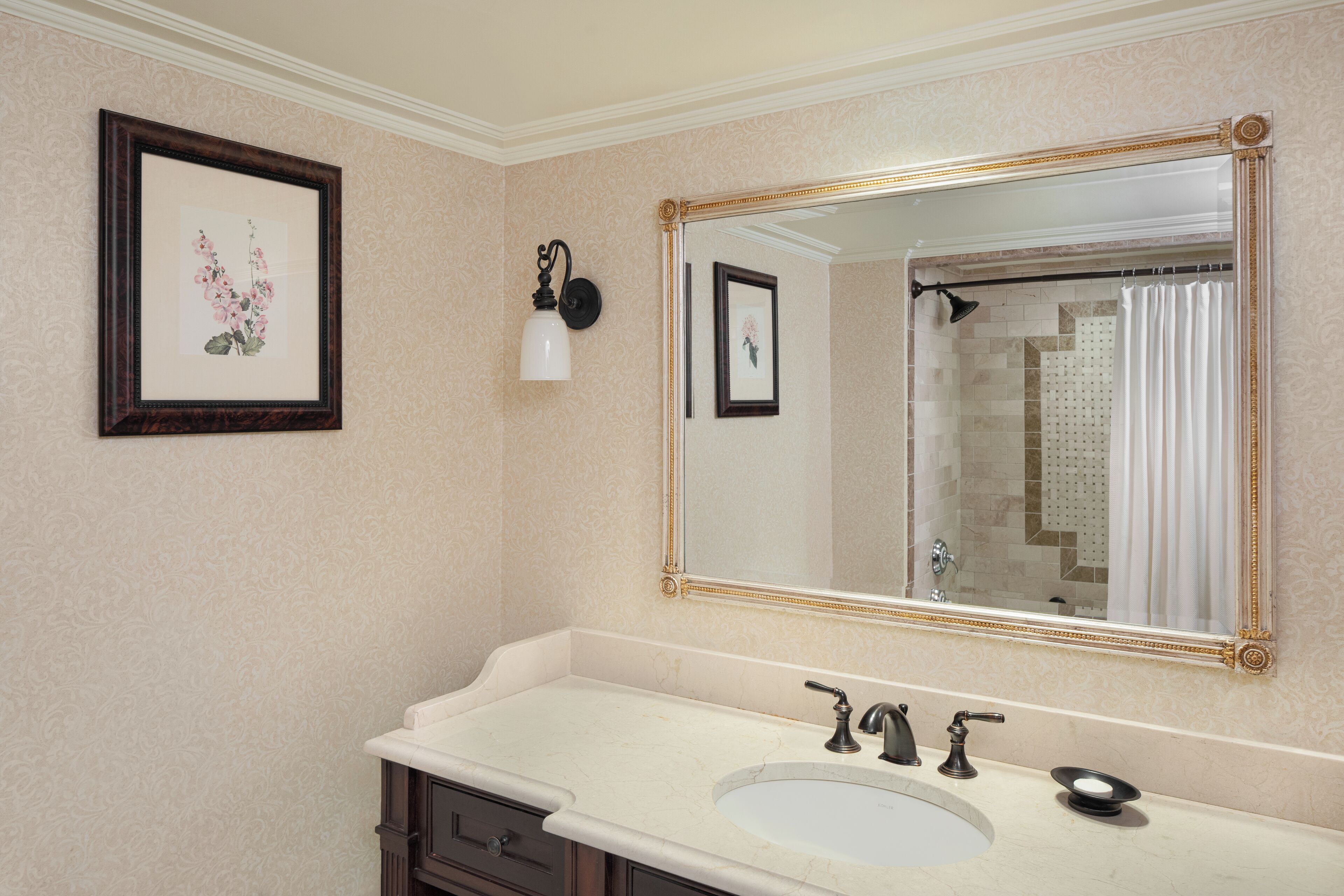 Un baño con un espejo grande, un lavabo y un cuadro en la pared.