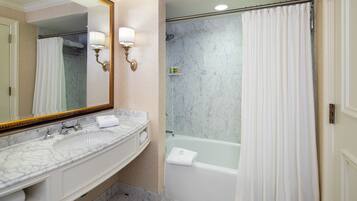 Un baño con lavamanos de mármol, bañera y cortina de ducha.