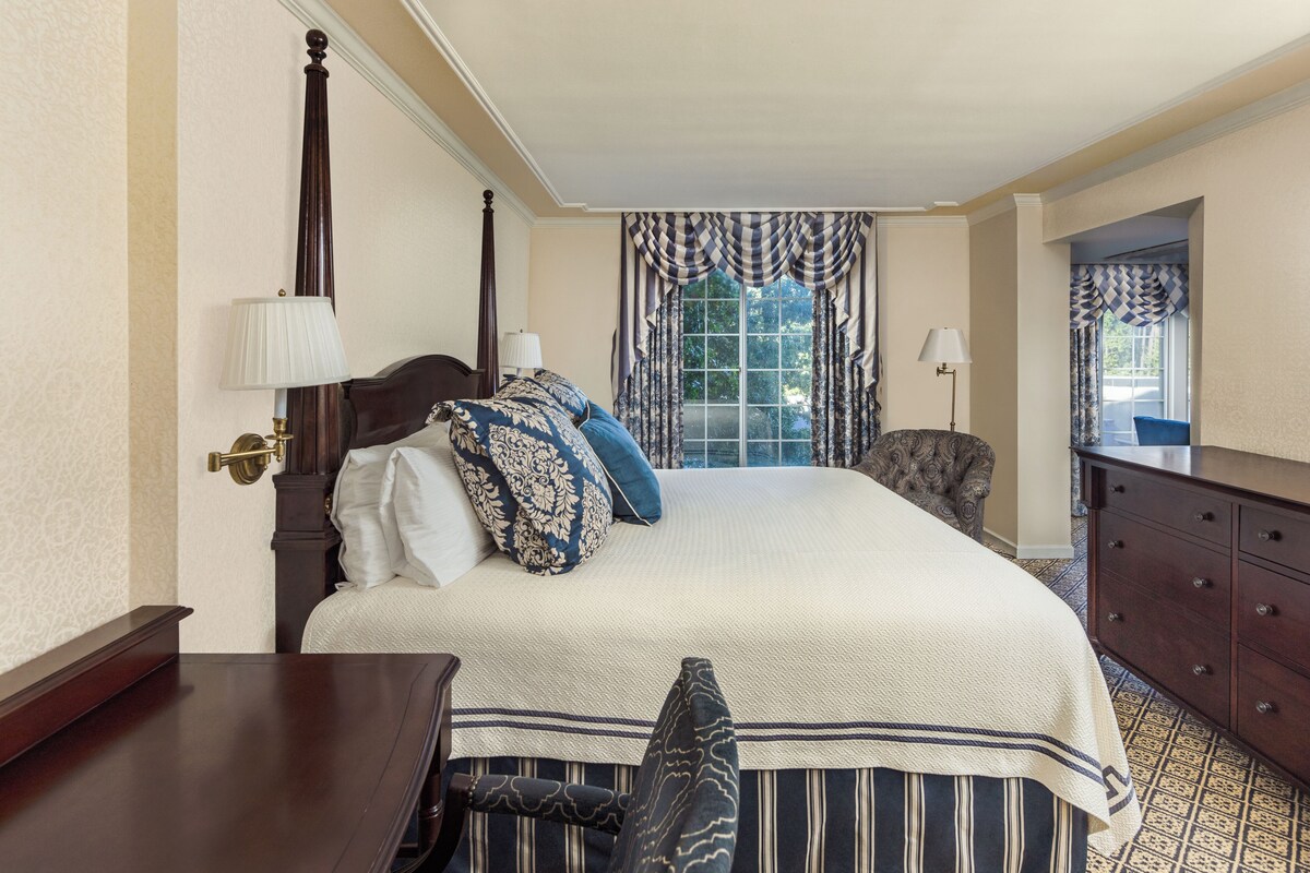 A neatly arranged bedroom with a large bed, a dresser, and a chair.
