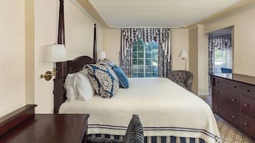 A neatly arranged bedroom with a large bed, a dresser, and a chair.