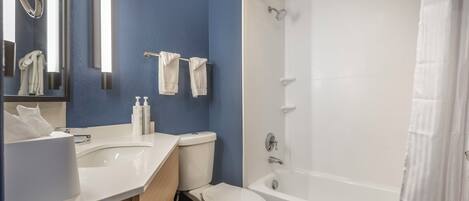 A bathroom with a white sink, toilet, and bathtub. There are two towels hanging on the wall.