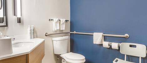 A bathroom with a white toilet, a blue wall, a white sink, and a white grab bar.