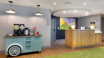 A reception area with a coffee station, a wooden counter, and a mural on the wall.