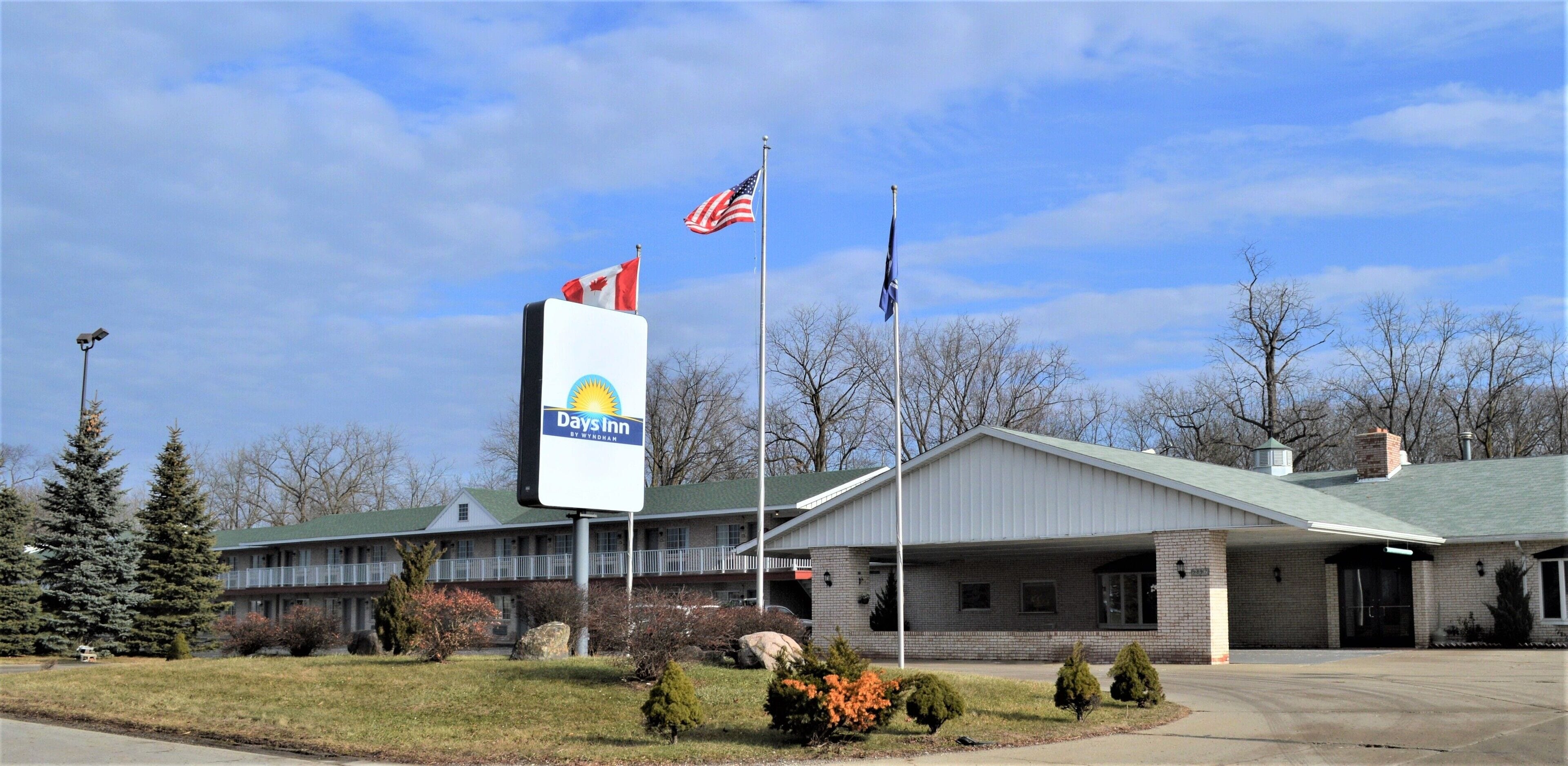 A Days Inn with a brick facade, a covered parking area, and a flagpole with the American flag.