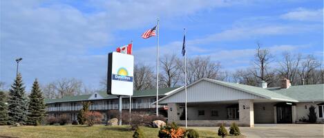 A Days Inn with a brick facade, a covered parking area, and a flagpole with the American flag.