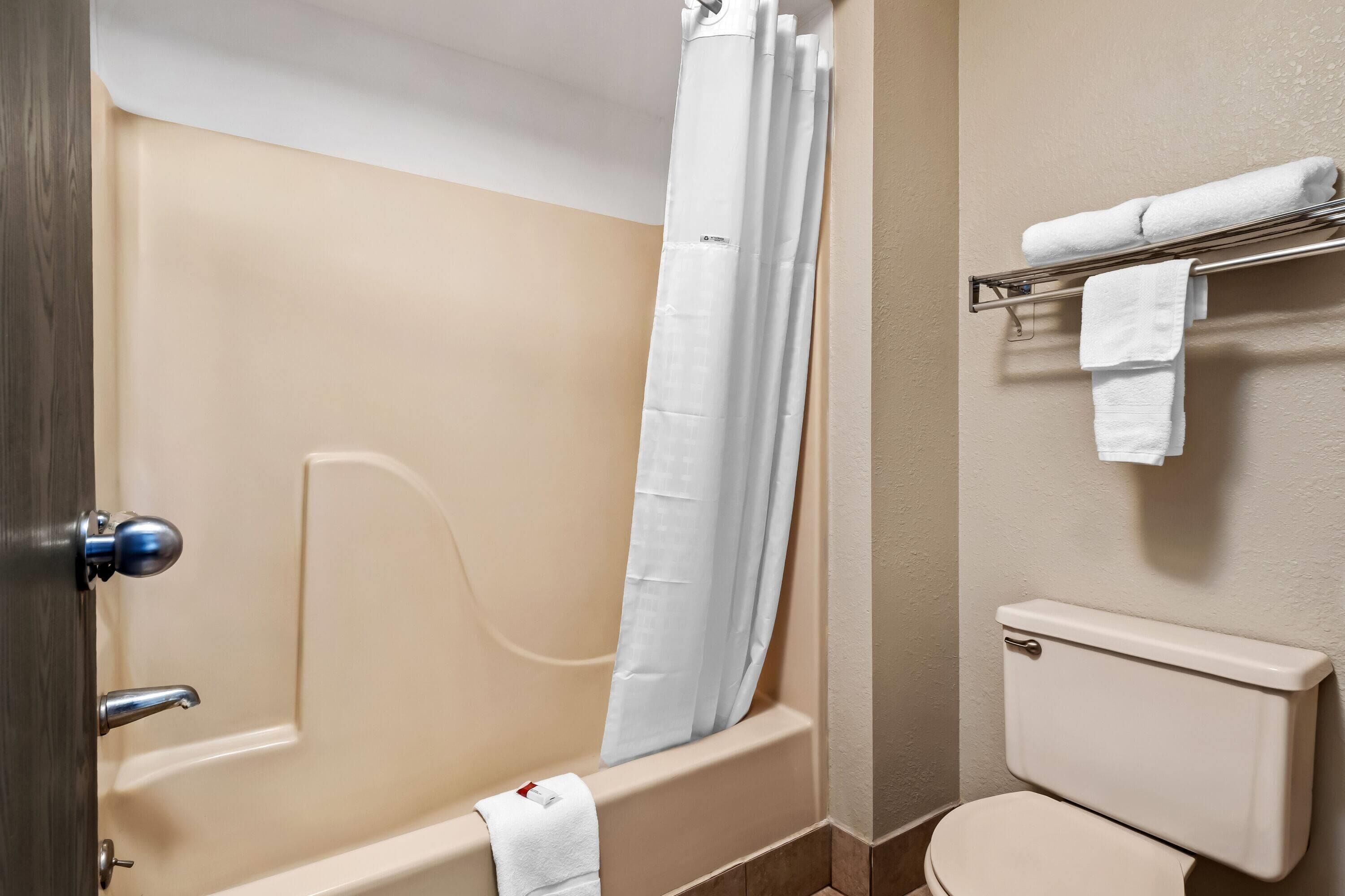 A bathroom with a bathtub, toilet, and towel rack.