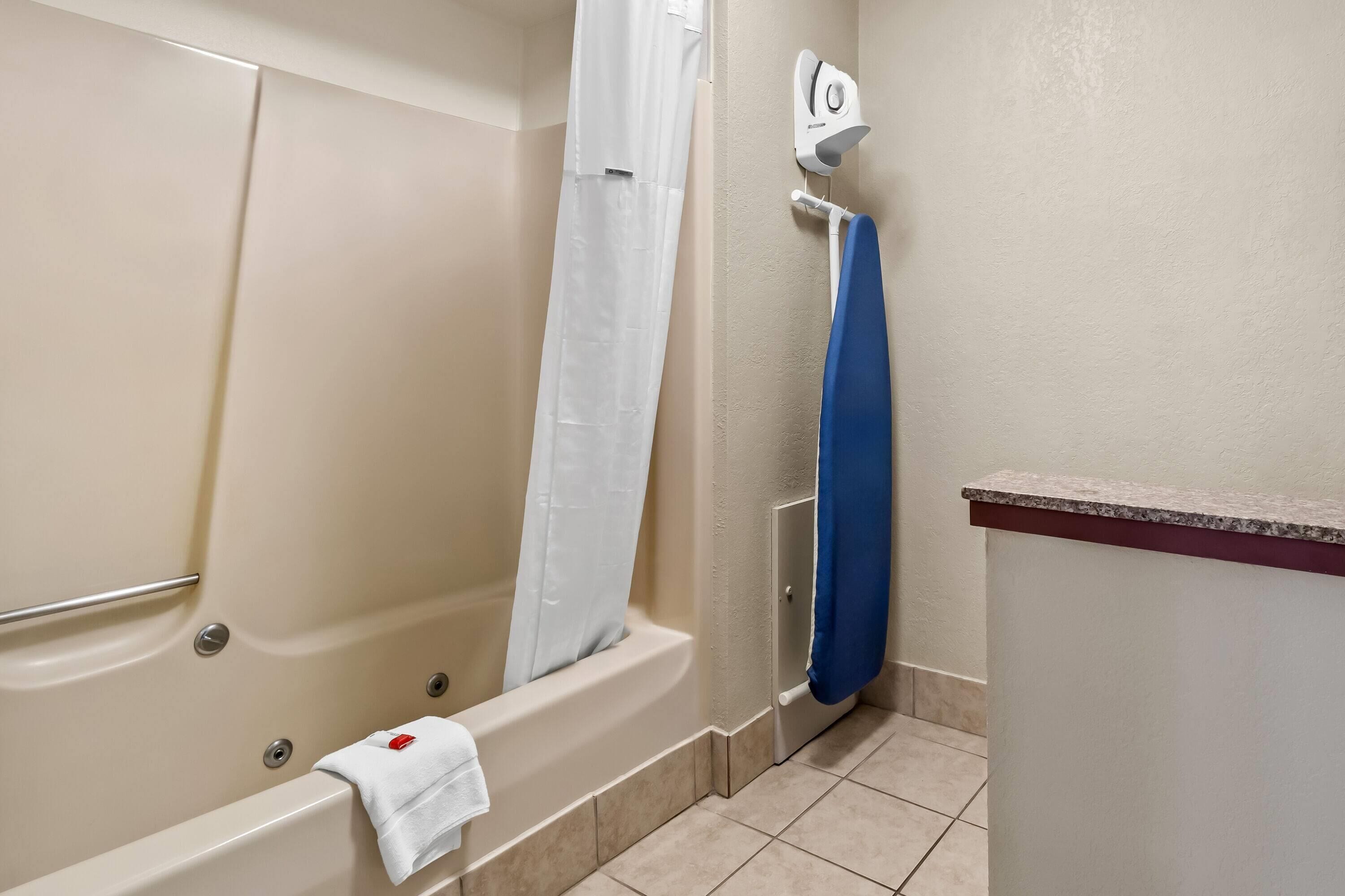 A bathroom with a bathtub, a shower curtain, a towel, and a hand dryer.