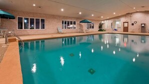 Ein überdachter Pool mit klarem Wasser, umgeben von Ziegelmauern und Fenstern.