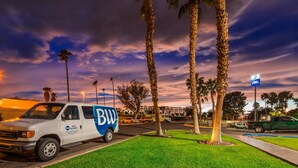 A white delivery van parked in a lot with palm trees and a sunset in the background. - Best Western Yuma Mall Hotel & Suites (Yuma)