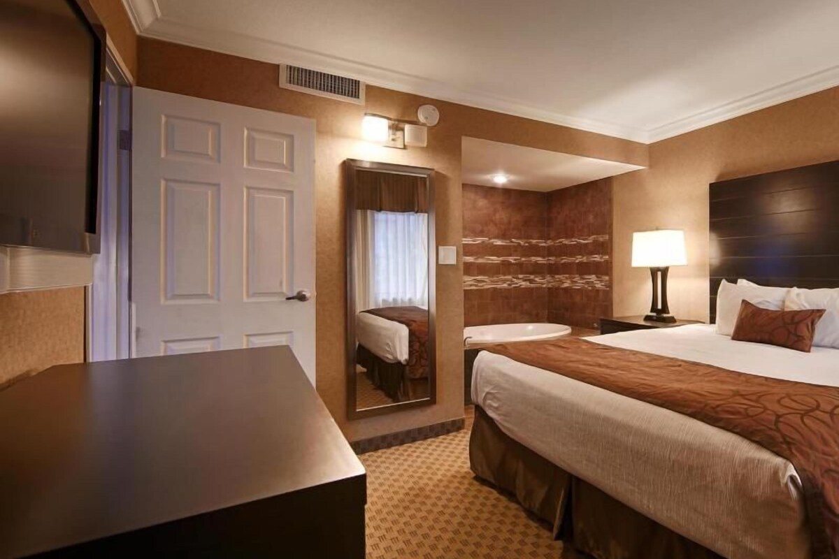 Una habitación de hotel con cama, mesita de noche, lámpara y espejo.