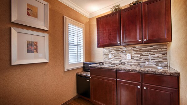 A kitchen with wooden cabinets, a tiled backsplash, and a dishwasher. - Best Western Yuma Mall Hotel & Suites (Yuma)