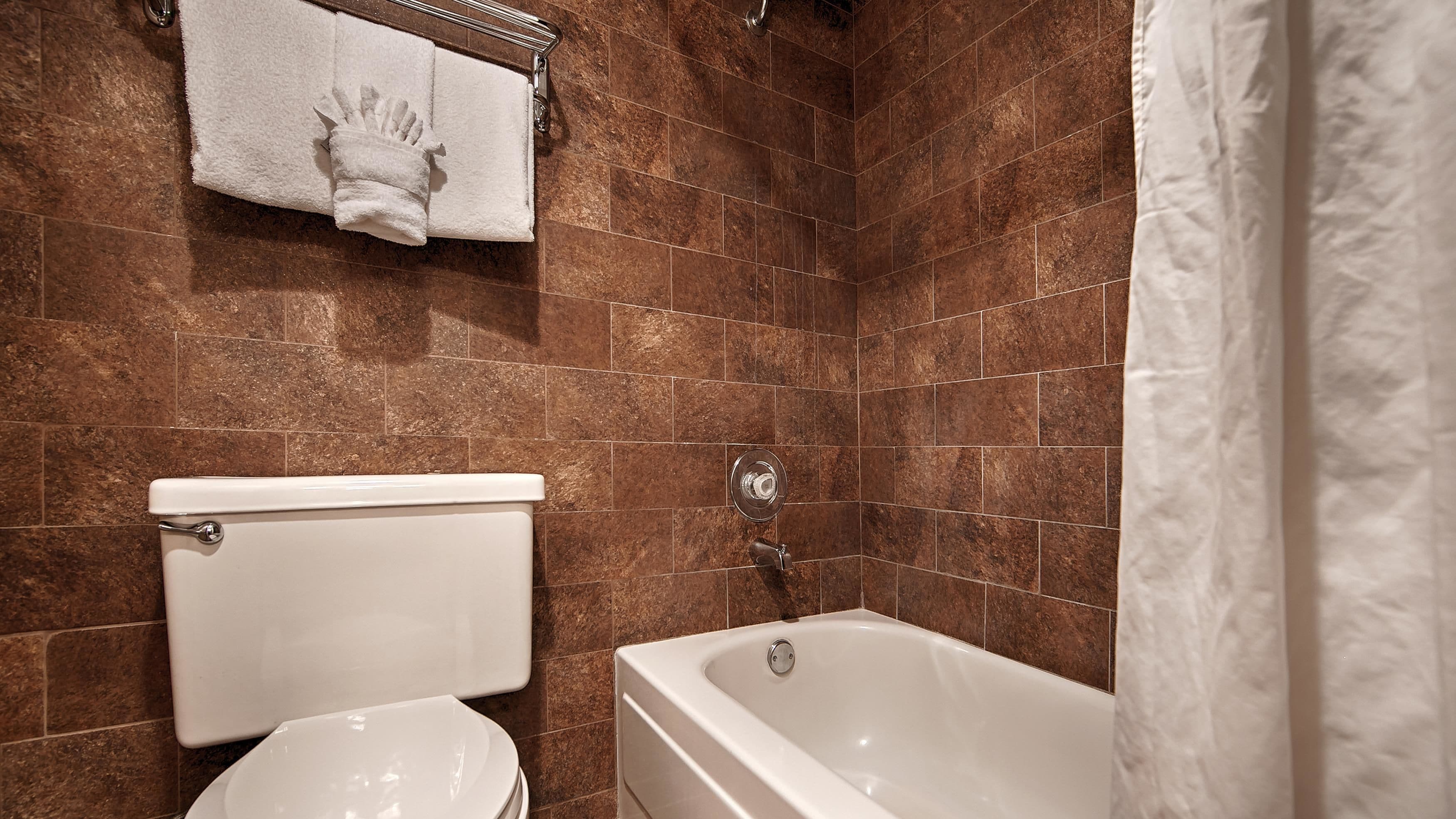 Ein Badezimmer mit Toilette, Badewanne und einem Handtuchhalter mit Handtuch.