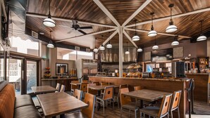 A restaurant with a high ceiling, exposed beams, and pendant lighting. Tables and chairs are arranged for dining. - Best Western Yuma Mall Hotel & Suites (Yuma)