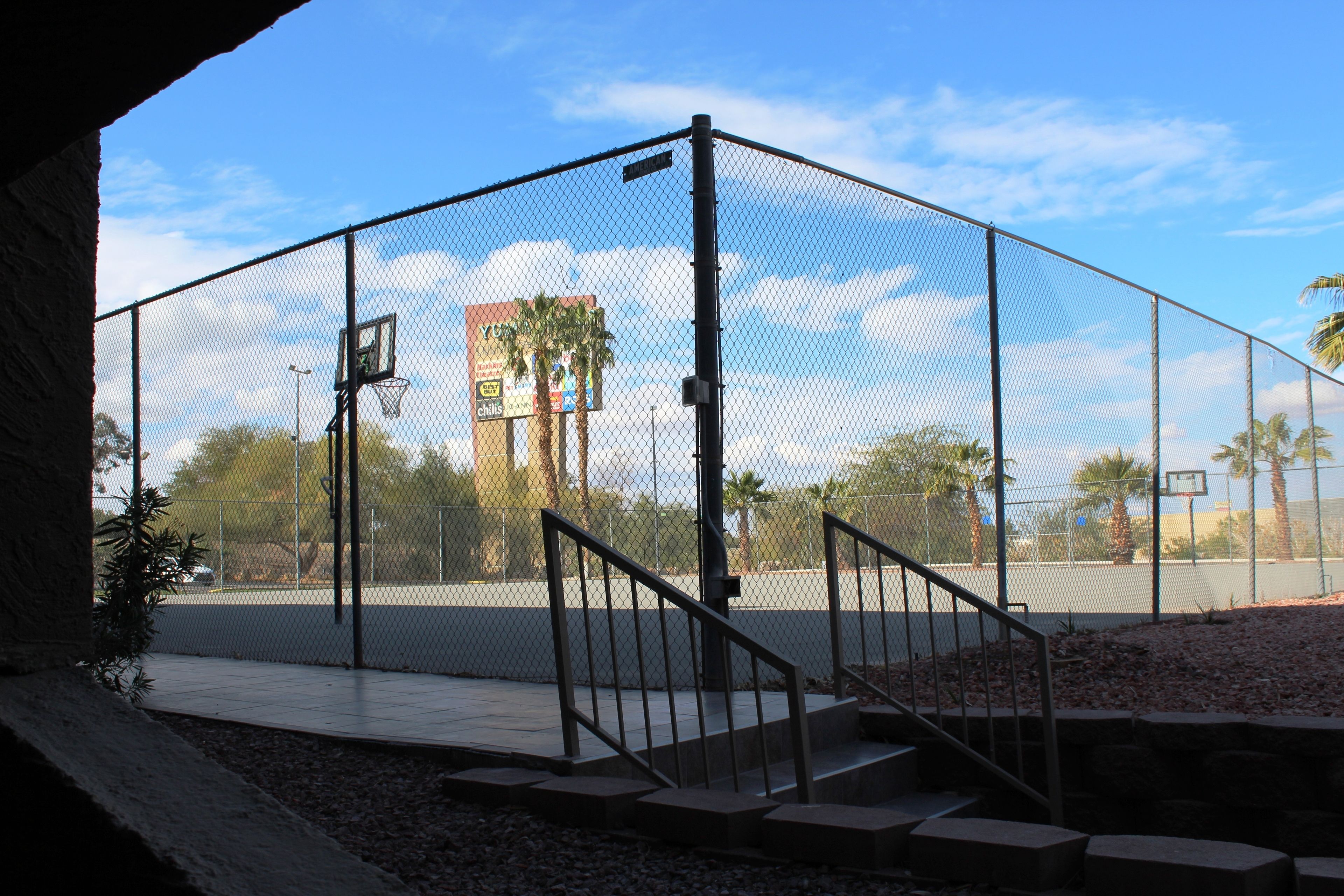 Un terrain de basket-ball entouré de clôtures, avec un escalier menant au terrain.