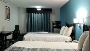 Habitación de hotel con dos camas, un escritorio, una silla, un microondas y una lámpara.