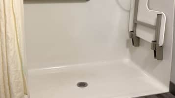 A white bathtub with a grab bar, a shower curtain, and a drain.