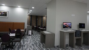 Un moderno vestíbulo de hotel con mostrador de recepción, zona de estar y vista al restaurante en el fondo.