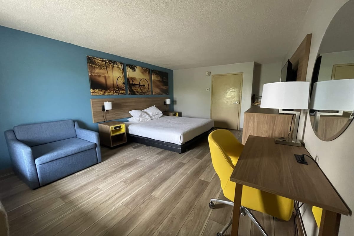 A hotel room with a bed, a sofa, a desk, and a chair.