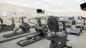 A gym with various exercise machines, including treadmills and elliptical trainers, arranged in rows. - Days Inn & Suites by Wyndham York (York)
