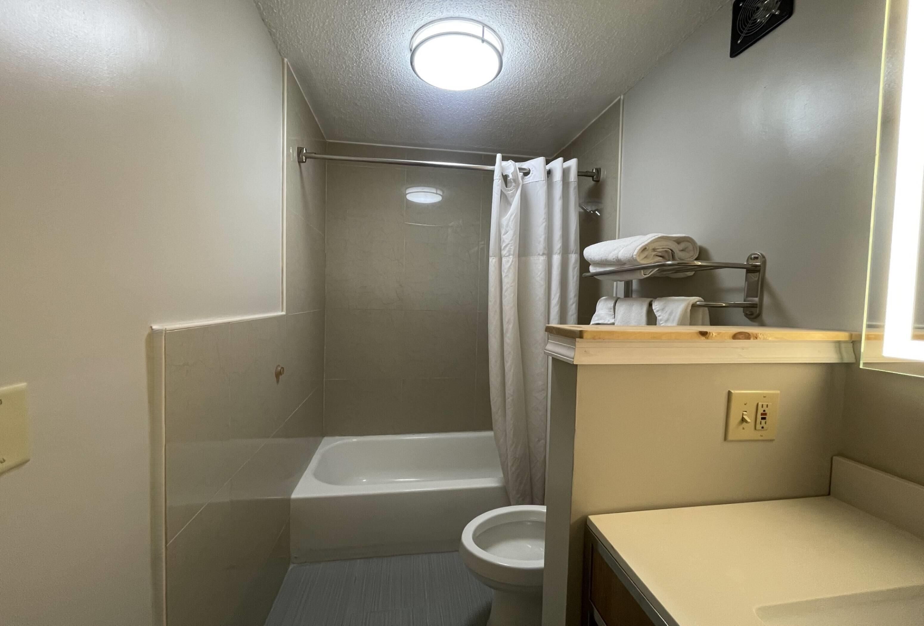 A small, compact bathroom with a bathtub, toilet, and a shower area.