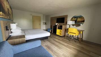 A hotel room with a bed, a desk, a chair, a TV, and a mirror.