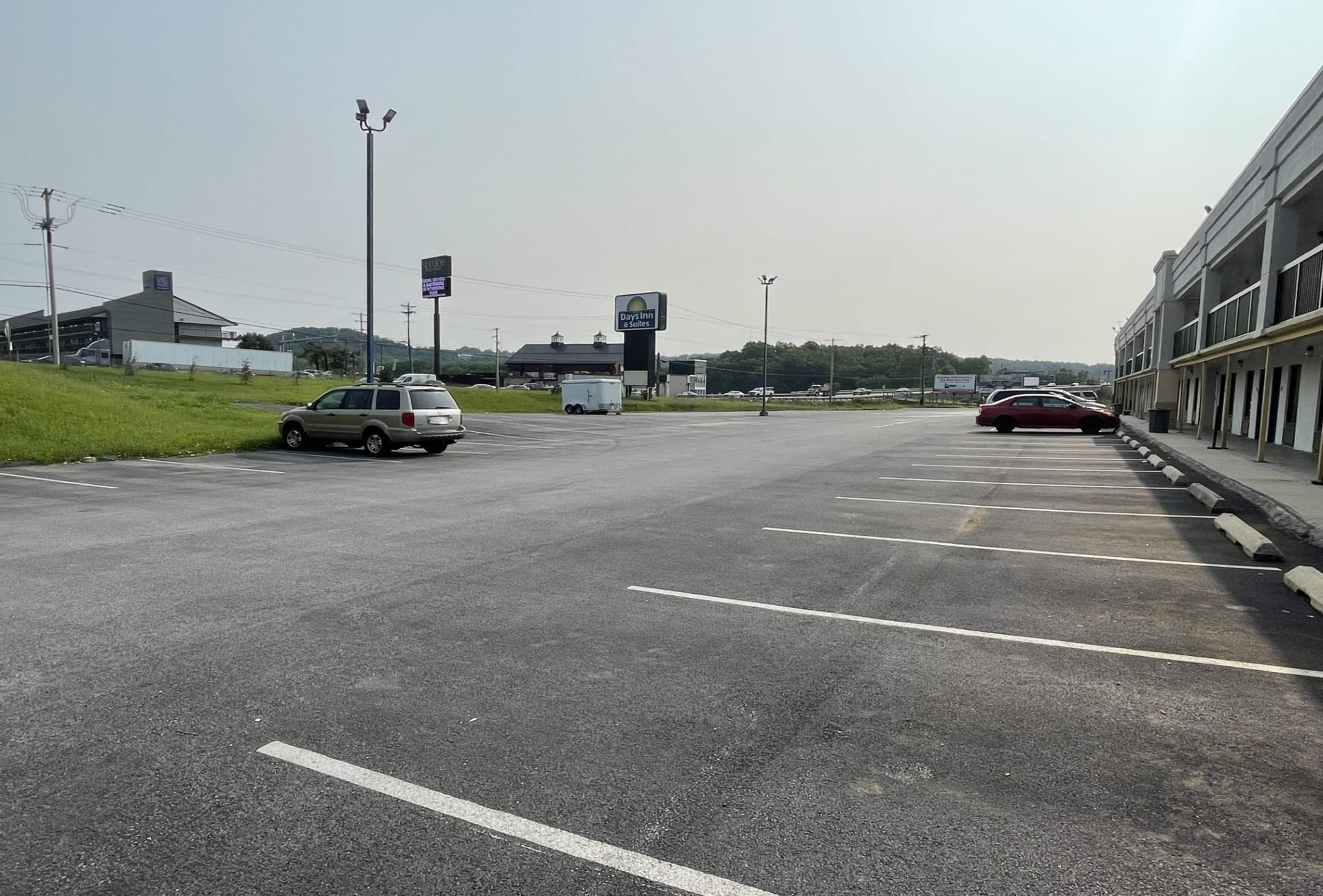 A parking lot with multiple vehicles, a Days Inn sign, and a building with a flat roof in the background.