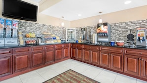 A commercial kitchen with a flat-screen TV, beverage dispensers, and a coffee machine. - Days Inn & Suites by Wyndham York (York)