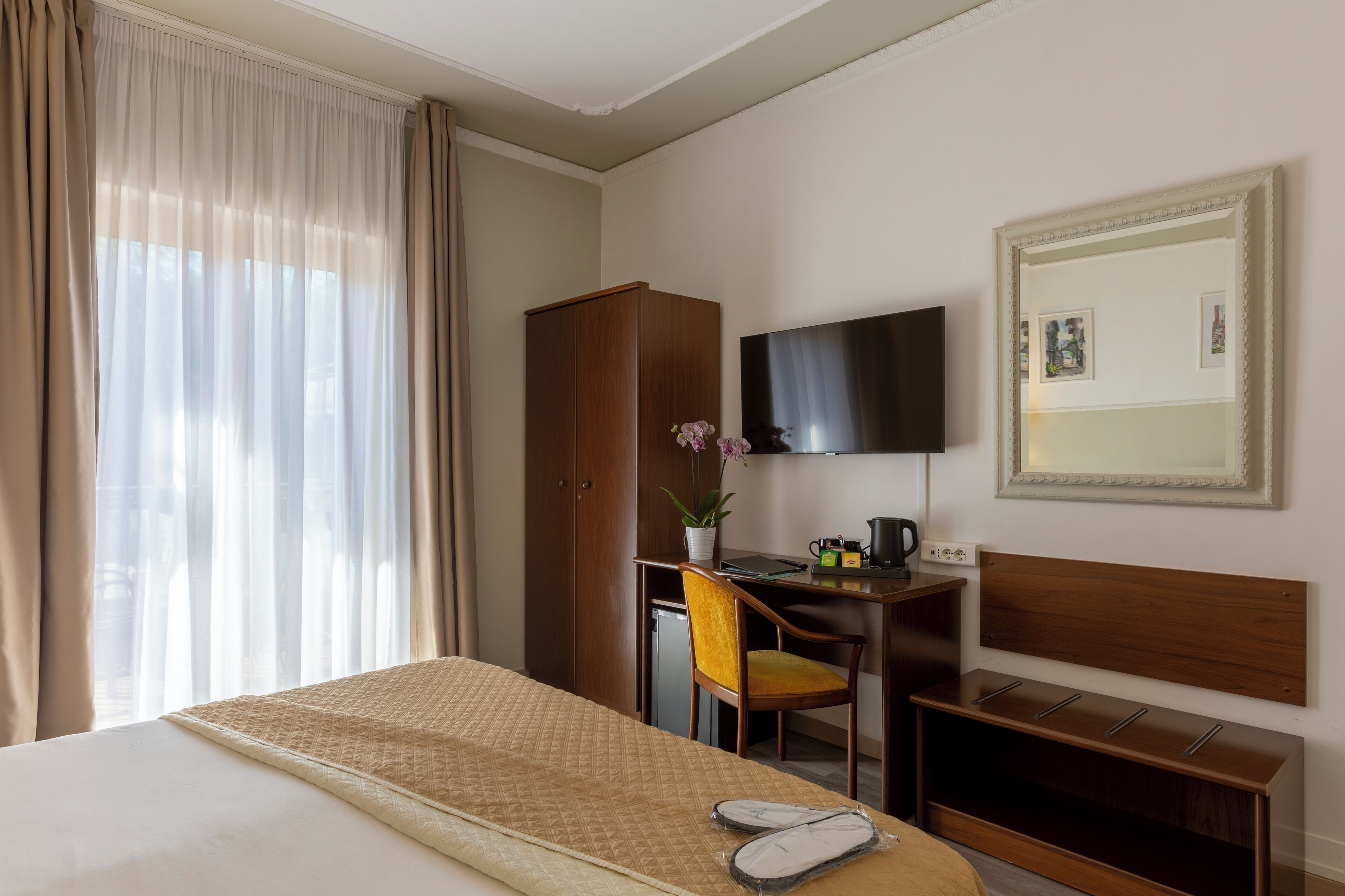 Une chambre d’hôtel comprenant un lit, un bureau avec une chaise, une télévision et une armoire.