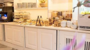 Un espace buffet pour le petit-déjeuner comprenant une machine à café, divers aliments et un réfrigérateur.