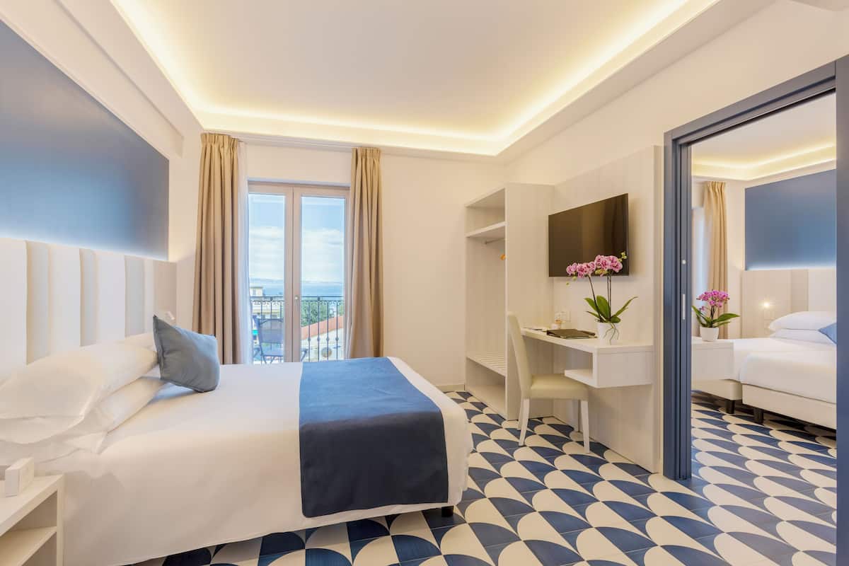 A hotel room with a bed, desk, and a large window with curtains.
