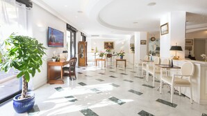 A spacious lobby with a marble floor, a reception desk, seating area, and a large potted plant. - Hotel Central Wellness (Sorrento)