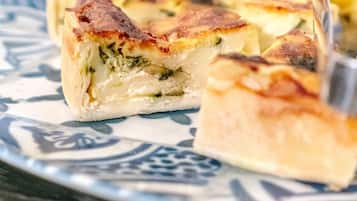 Una porció de quiche amb una crosta daurada sobre un plat estampat.